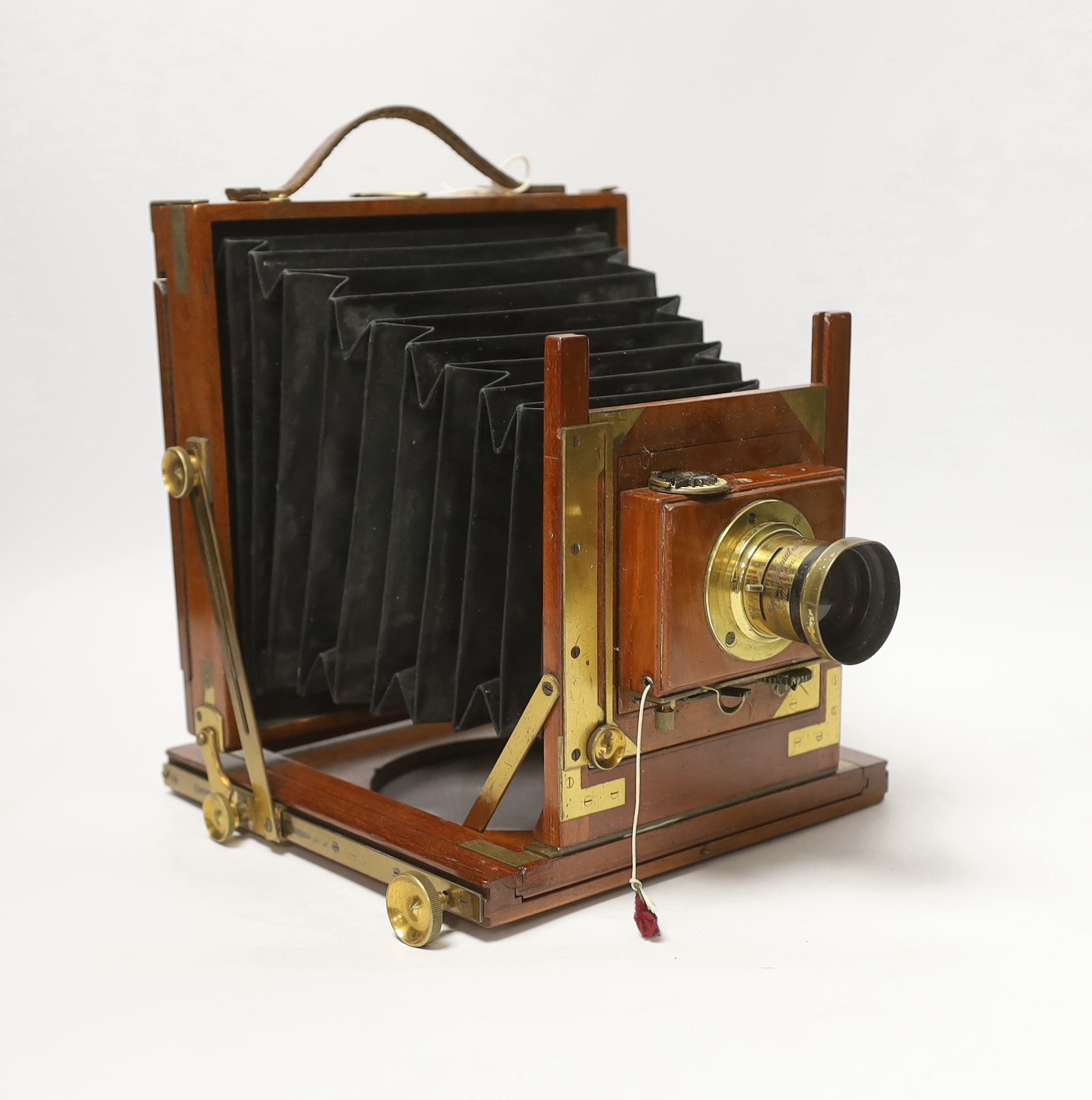 A late nineteenth century brass and mahogany half plate bellows camera with a lens and a shutter action by Thornton Pickard